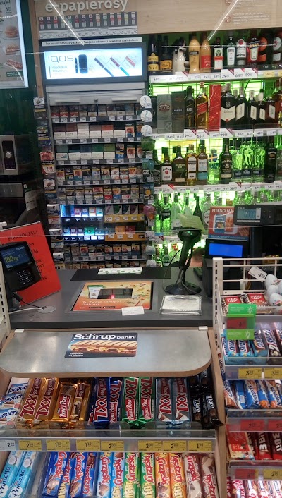 Żabka wnętrze, e-papierosy na półce, kolorowe jednorazówki za kasjerem, sklep convenience vape display - Żabka